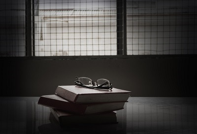 image of reading glasses on a stack of books inside a prison