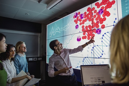 instructor teaching students using large screen featuring scientific data